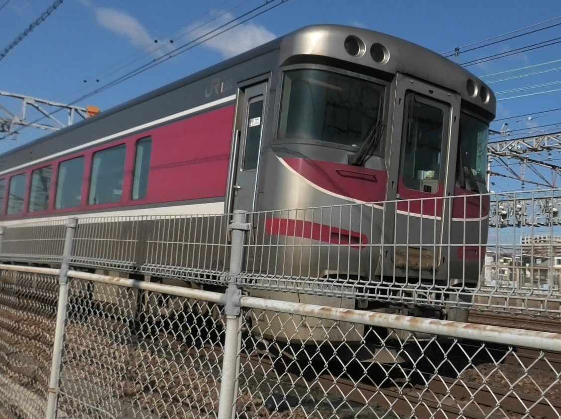 柵ごしに見えるキハ189系。銀色の車体に赤紫の帯