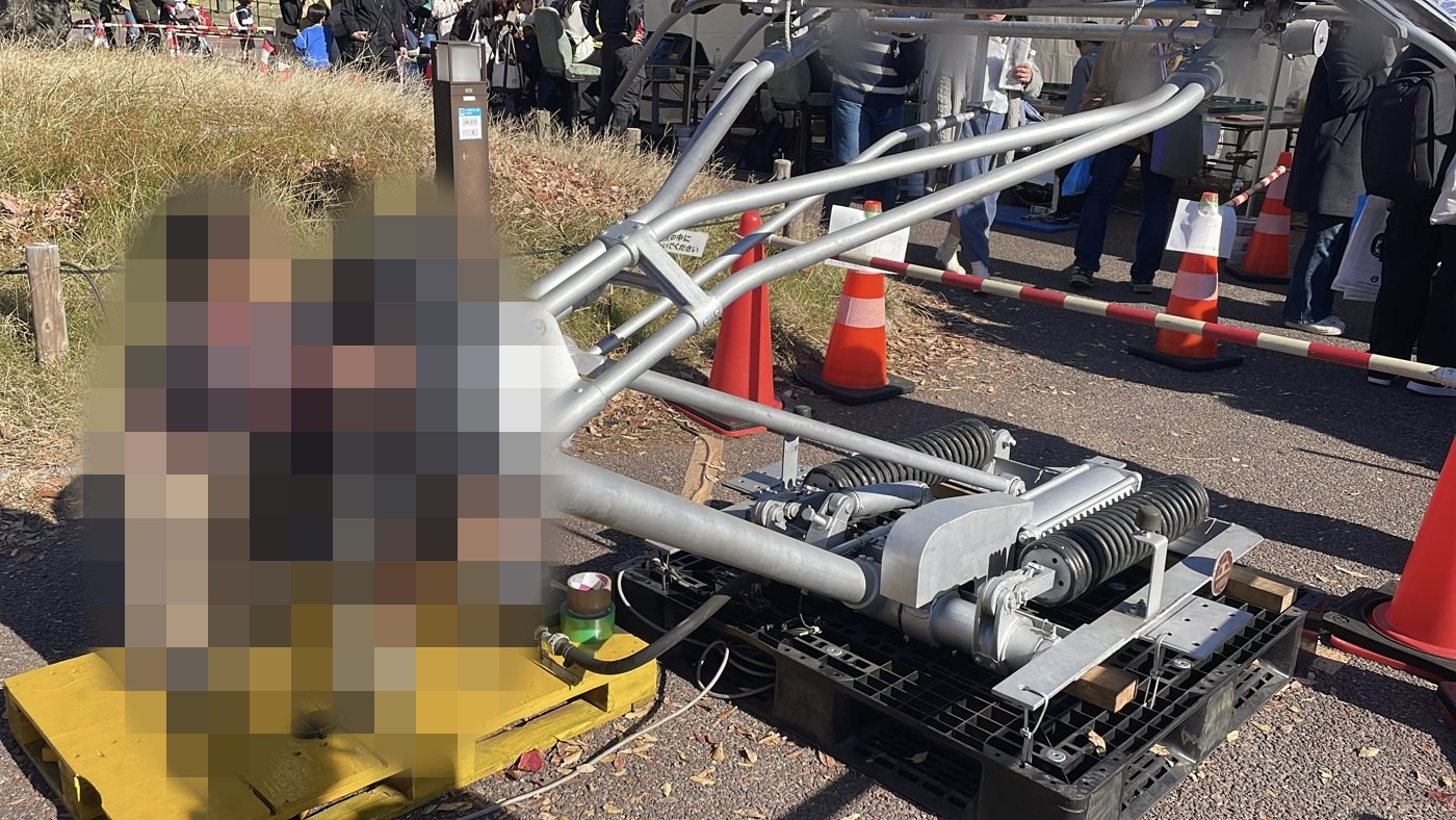 万博鉄道まつり2025で、実物のパンタグラフをポンプで動かす展示を体験する子ども