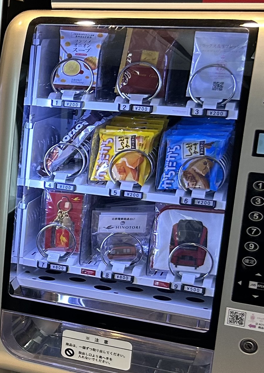 ひのとり車内の自動販売機。上段はお菓子、下段にひのとりグッズが並ぶ