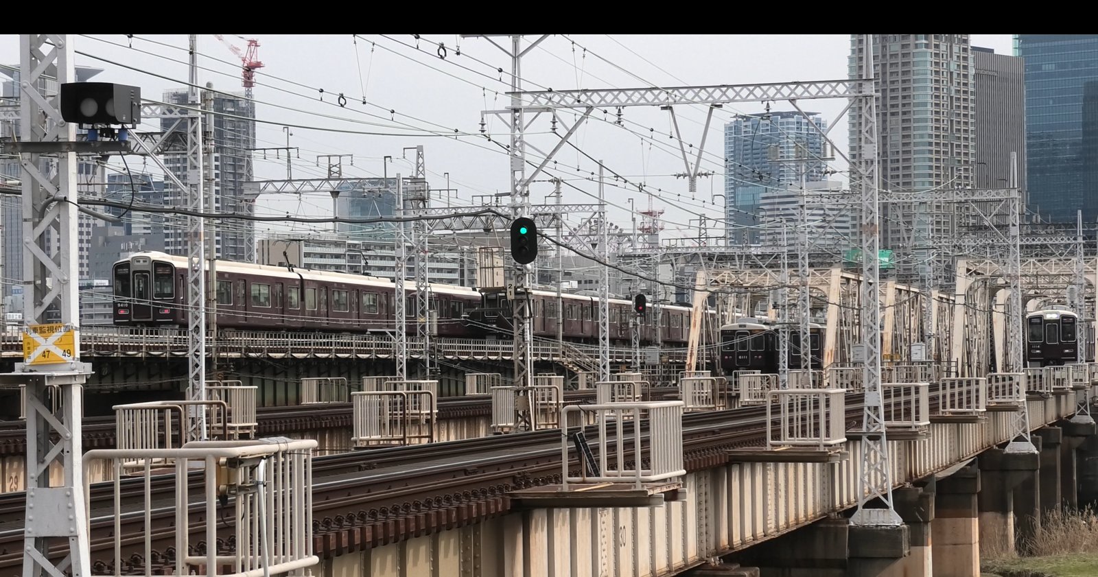 淀川の鉄橋を渡る複数の阪急電車と大阪のビル群
