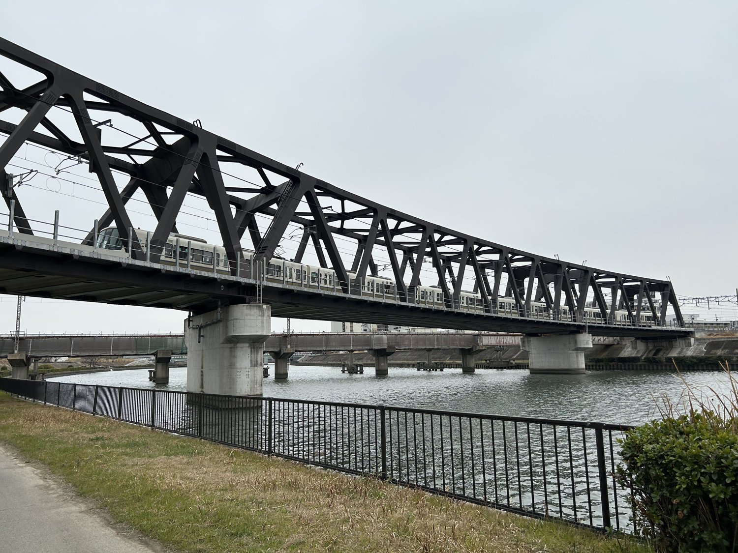 神崎川の堤防から見た神崎川橋梁（トラス橋）を渡る列車