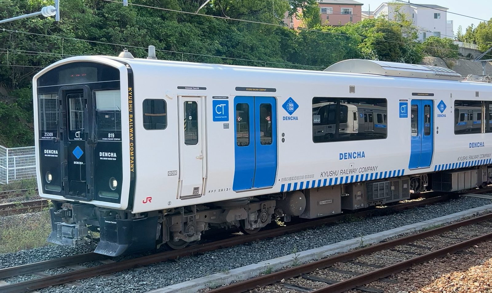 JR香椎駅に停車する蓄電池電車DENCHA（BEC819系・白と青の車体）。背景にもう1本のDENCHA