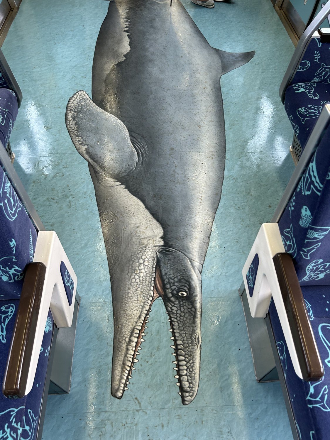 めでたいでんしゃ かなたの車内。床に描かれた大きなクジラのアートと、海の生きものがデザインされたシート