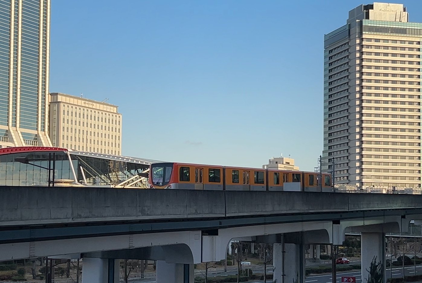 トレードセンター前駅付近の高架を走るオレンジ色のニュートラム200系
