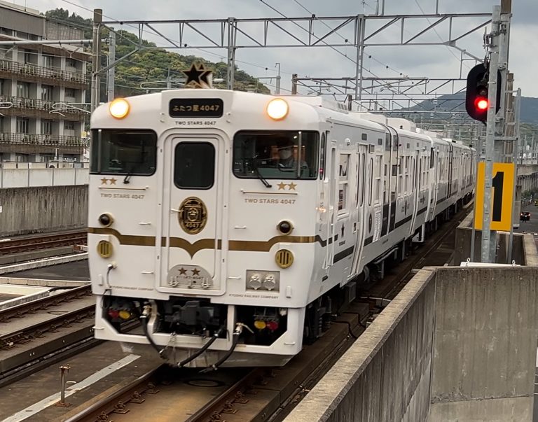 武雄温泉駅に入線する観光列車「ふたつ星4047」（白と金の車体）