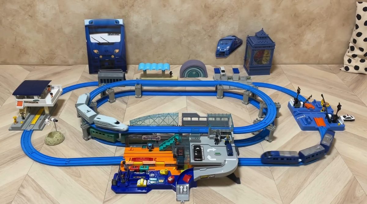 ビッグステーションで遊んでいる動画の一場面。中央に改札とエスカレーター、駐車場のある大きな駅を置き、まわりを高架のレールが囲んでいる